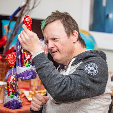 Ein Mann hält eine Geschenktüte mit Schokoladen-Nikolaus in der Hand.