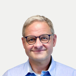 Portr&auml;taufnahme von Franz Str&ouml;bitzer, Standortleitung Maria Ponsee bei BALANCE. Er blickt mit einem herzlichen L&auml;cheln direkt in die Kamera. Er hat kurzes, grau meliertes Haar und tr&auml;gt eine dunkle, rundliche Brille sowie ein hellblaues Hemd vor einem neutralen, hellen Hintergrund.