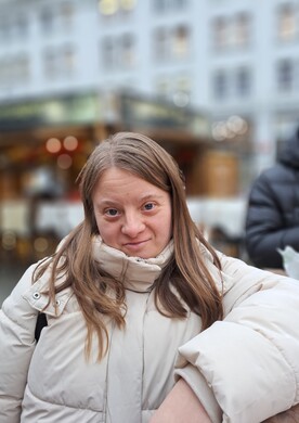 Eine junge Frau mit Behinderung blickt selbstbestimmt in die Kamera.