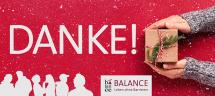 Schriftzug "DANKE!" zwei Hände halten ein Geschenkspaket, Logo von BALANCE